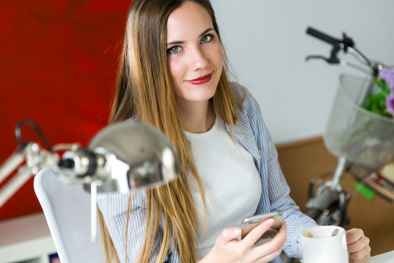 Beautiful young woman using her mobile phone in the office